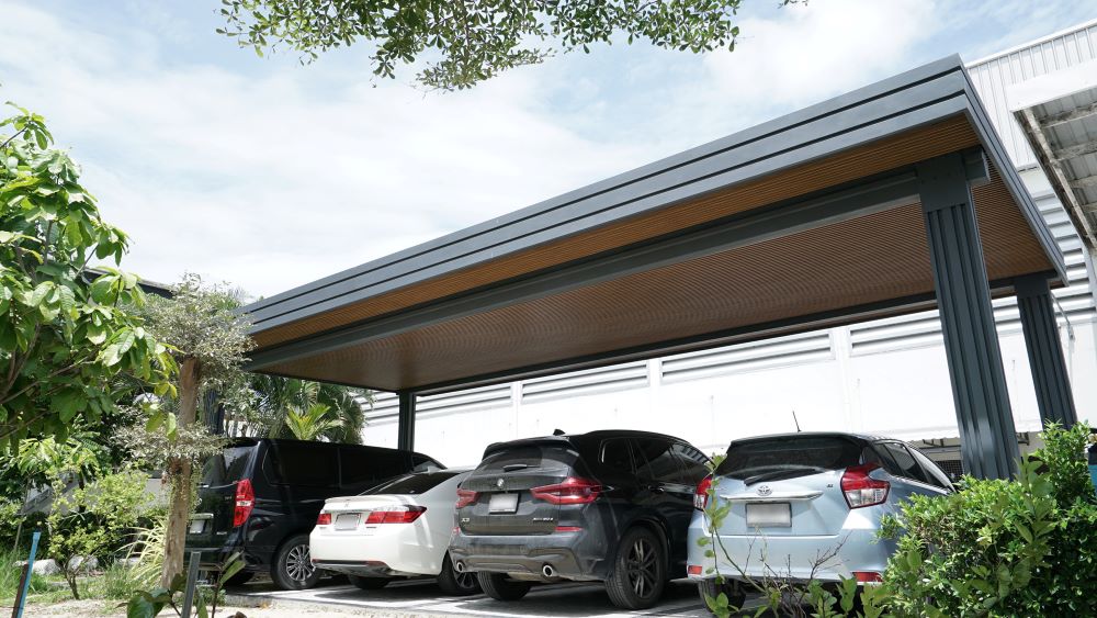 โรงรถที่ใช้หลังคาไวนิลท้องเรียบผสานกับไม้ระแนงตกแต่งใต้หลังคา เพิ่มความสวยงาม