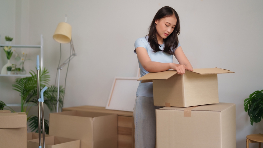 ผู้หญิงเก็บของที่ไม่ใช้ลงกล่อง ก่อนทำการตกแต่งบ้านให้น่าอยู่ขึ้น